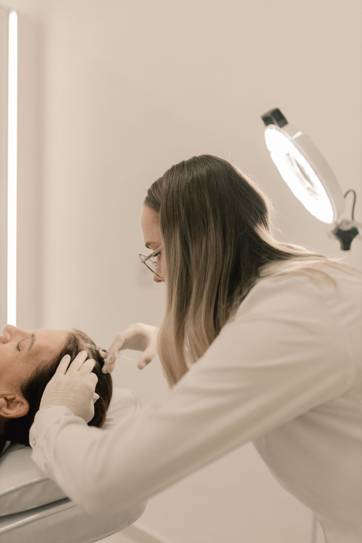 Fachperson untersucht die Kopfhaut einer Patientin